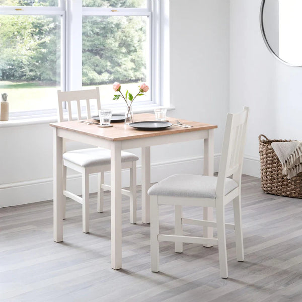 Dining area with a wooden table and white chairs in a bright room.