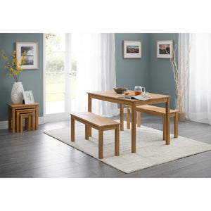Wooden dining set with table and benches in a room with light blue walls and large windows.