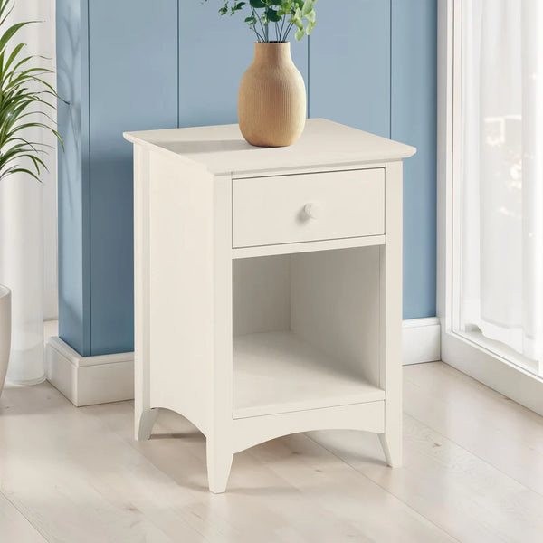 White nightstand with a vase and plant against a blue wall
