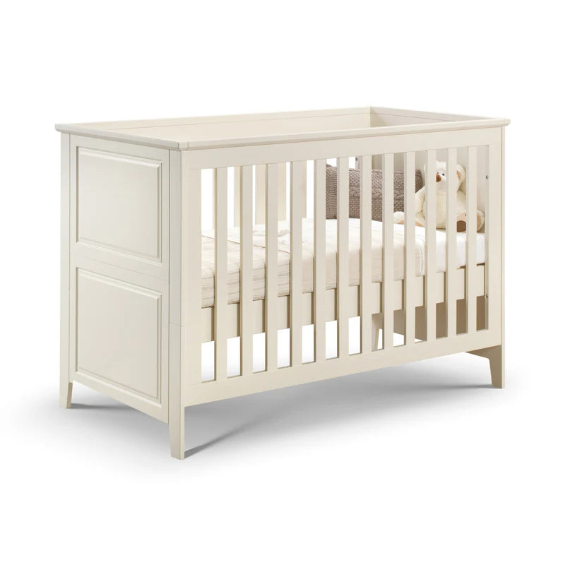 White crib with a teddy bear inside on a white background