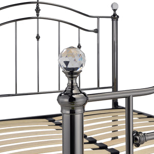 Metal bed frame with decorative headboard post and crystal ball finial.