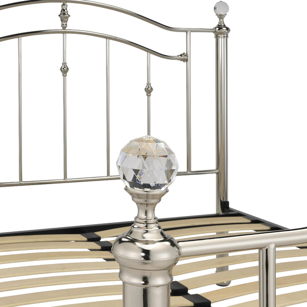 Metal headboard with decorative crystal finial on a white background