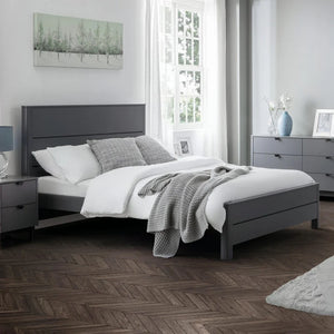 Modern bedroom with gray bed frame, white bedding, and wooden flooring.