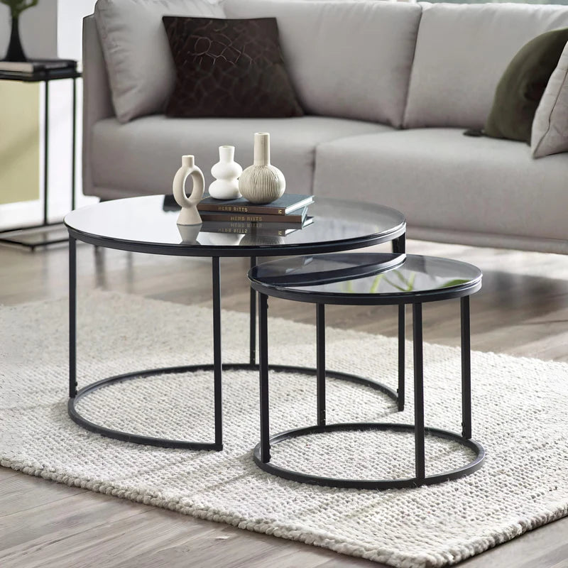 Set of two round glass coffee tables with black metal frames on a white background