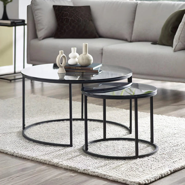Modern black nesting tables in a living room setting with a sofa and decorative items.
