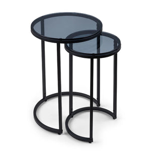 Set of two black metal nesting tables with glass tops on a white background