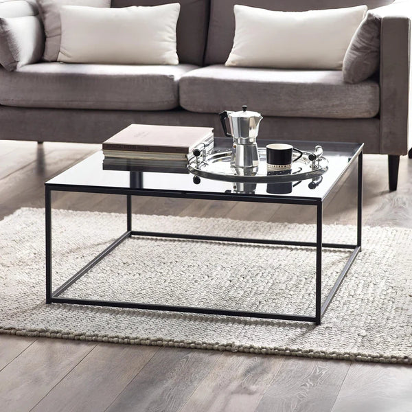 Modern living room with a glass coffee table, books, and a teapot.