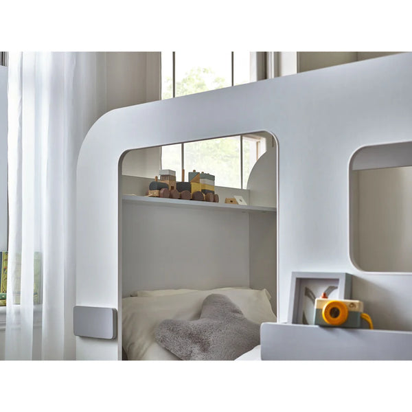 White children's bunk bed with toys in a bright room