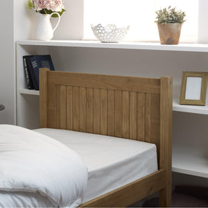 Wooden headboard with white bedding against a white wall with decorative items.