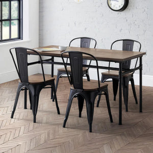 Dining area with wooden table and black metal chairs on a herringbone wood floor.