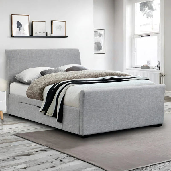 Gray upholstered bed in a room with framed pictures on the wall.