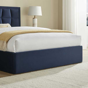 Navy bed frame with white mattress and beige blanket in a room setting.