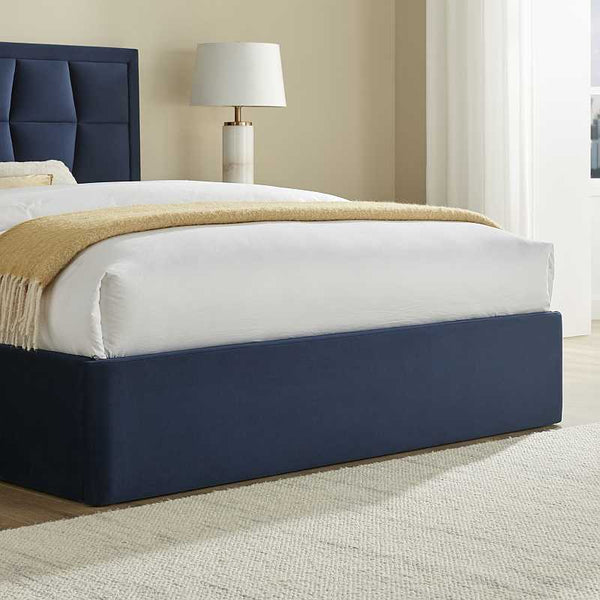 Navy bed frame with white mattress and beige blanket in a room setting.