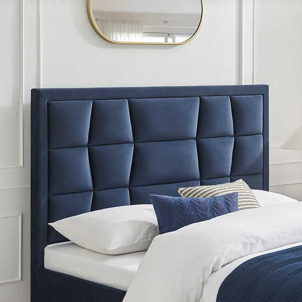 Blue upholstered headboard with pillows on a bed in a bedroom setting.
