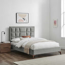 Gray upholstered bed in a bedroom with wooden nightstand and framed art on wall.