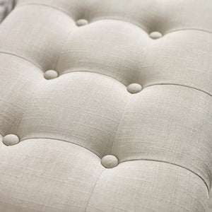 Close-up of a tufted beige fabric surface with button details
