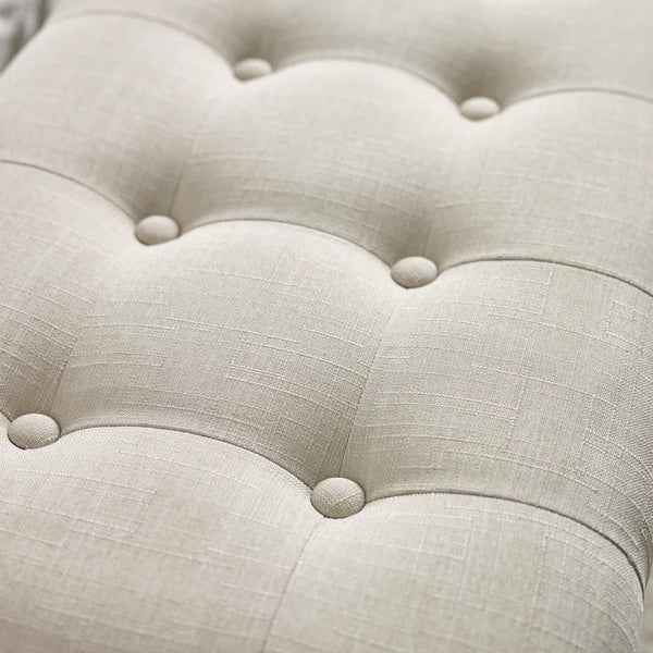 Close-up of a tufted beige fabric surface with button details