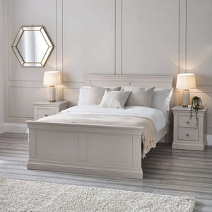 Neatly made bed in a bedroom with two nightstands and lamps.