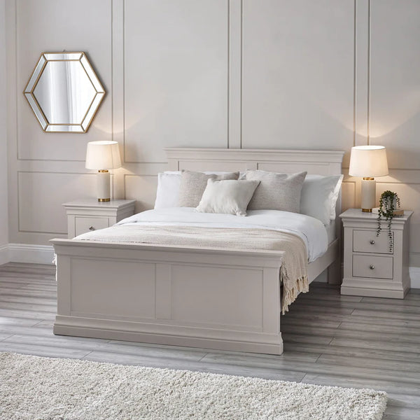 Neatly made bed in a bedroom with two nightstands and lamps.