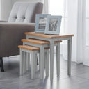 Set of three nesting tables with wooden tops and gray bases in a living room setting.