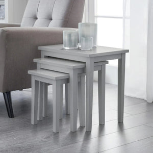 Set of three gray nesting tables with glass candle holders in a living room setting.