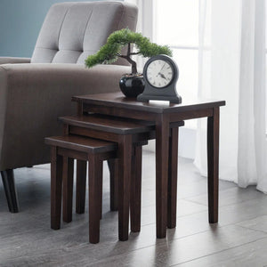 Set of four dark wood nesting tables in a living room setting with a chair and decorative items.