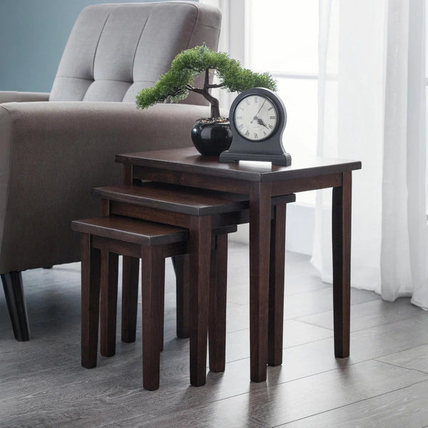 Set of four dark wood nesting tables in a living room setting with a chair and decorative items.