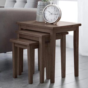 Set of three wooden nesting tables with a clock on top in a living room setting.