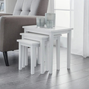 Set of white nesting tables with glass holders in a living room setting.