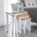 Set of three nesting tables with wooden tops and white bases in a living room setting.