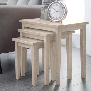 Set of three wooden nesting tables with a clock on top in a room setting.