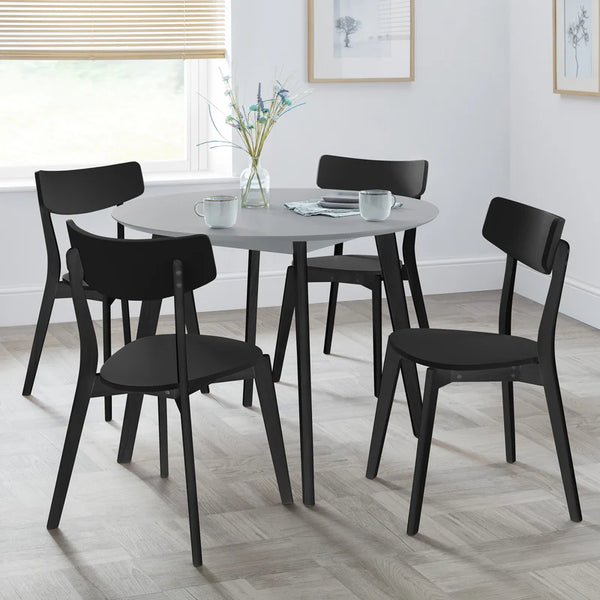 Dining table set with six black chairs in a room with light wood flooring and white walls.
