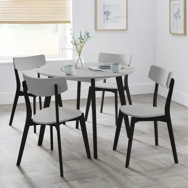 Dining table set with chairs in a room with light wood flooring and white walls.