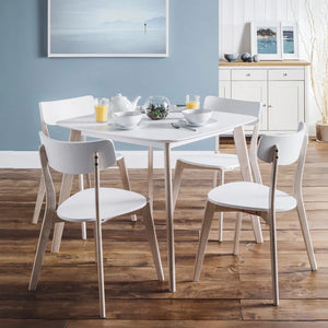 Dining area with a round table and chairs in a room with a blue wall and wooden floor.