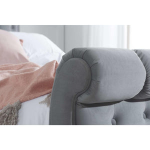 Gray upholstered rolled foot end in a bedroom setting