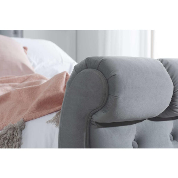 Gray upholstered rolled foot end in a bedroom setting