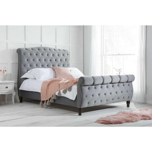 Gray upholstered bed with tufted design in a bedroom setting.