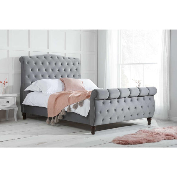 Gray upholstered bed with tufted design in a bedroom setting.