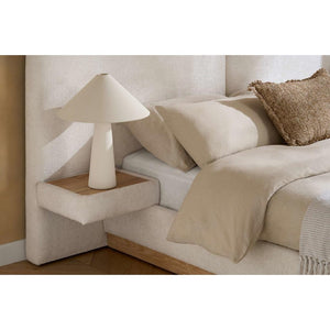 Beige bedroom with a bed, lamp, and decorative pillow.