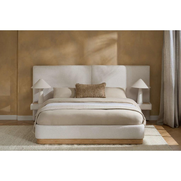 Beige bed with matching headboard and nightstands in a room with a brown wall and white rug.
