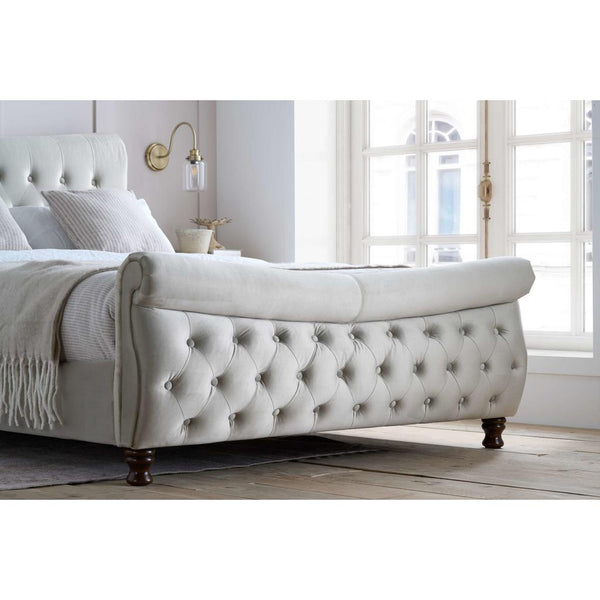 White tufted bed in a bright bedroom with large windows.