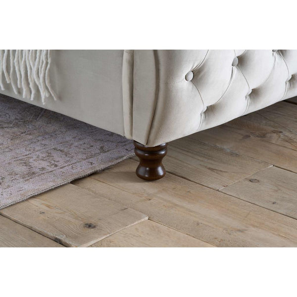 Buttoned bed frame with wooden legs on a wooden floor