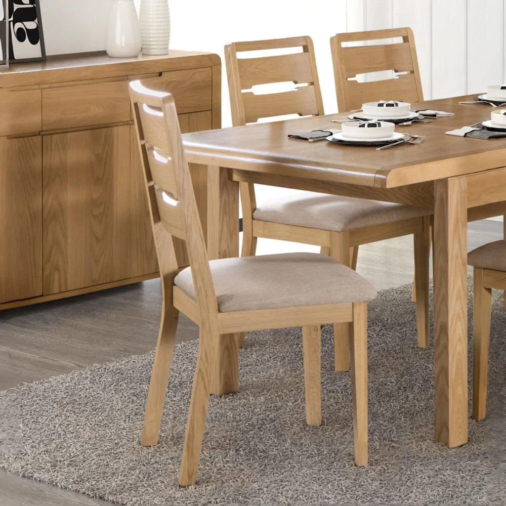 Two wooden chairs with beige cushioned seats on a white background