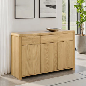 Light wood sideboard in a modern living room with a plant and artwork.