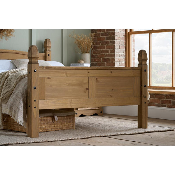 Wooden bed in a room with a window and brick wall.