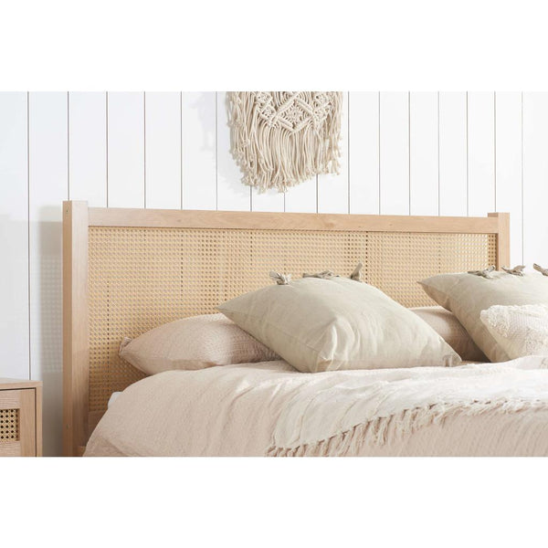 Bed with wicker headboard and white bedding against a white wall.