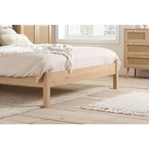 Wooden bed in a room with light-colored walls and wooden flooring.