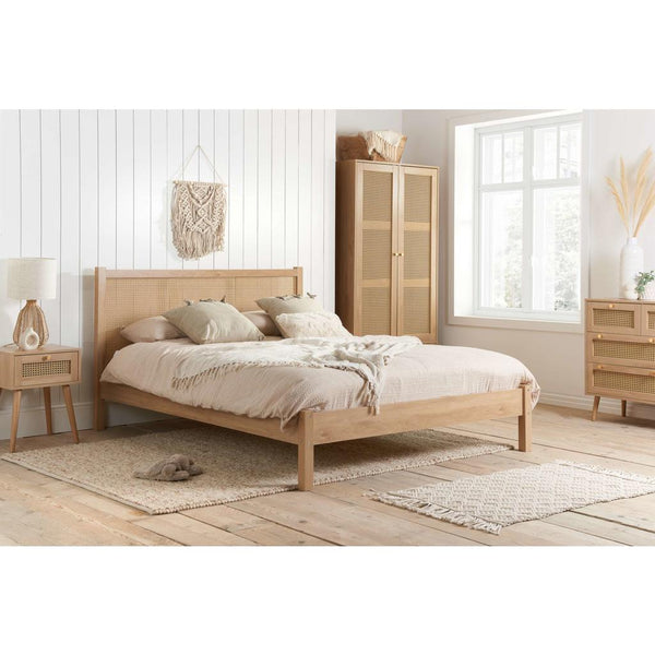 Wooden bedroom furniture set with bed, wardrobe, and side table in a bright room.