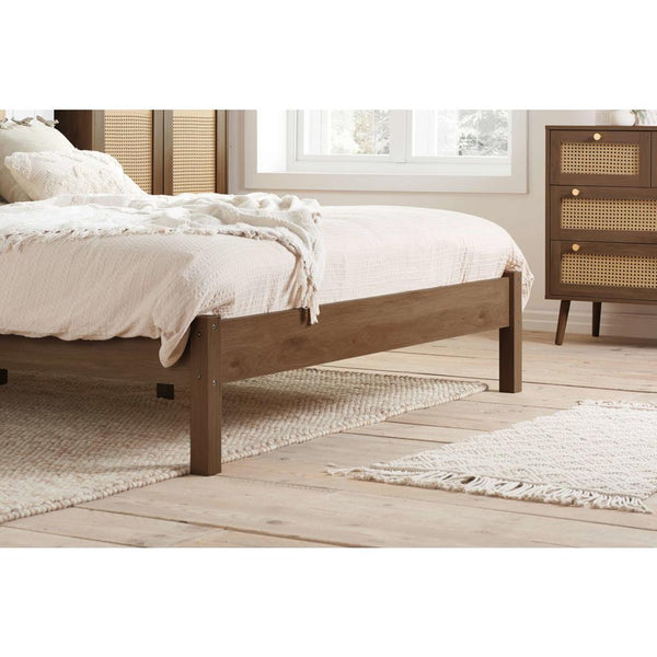 Wooden bed frame in a bedroom setting with a dresser and window.