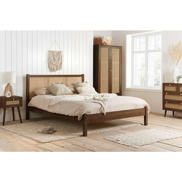 Wooden bed in a bedroom setting with a wardrobe and side table.